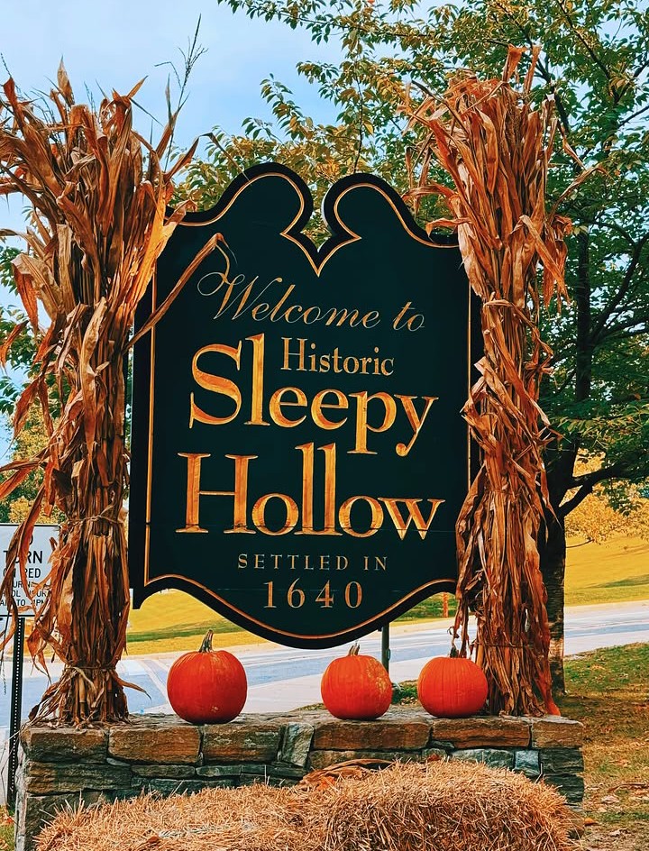 Placa histórica de boas-vindas a Sleepy Hollow cercada de abóboras e milho seco